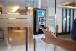 Wall-mounted biometric attendance device with a glowing green fingerprint scanner and digital display